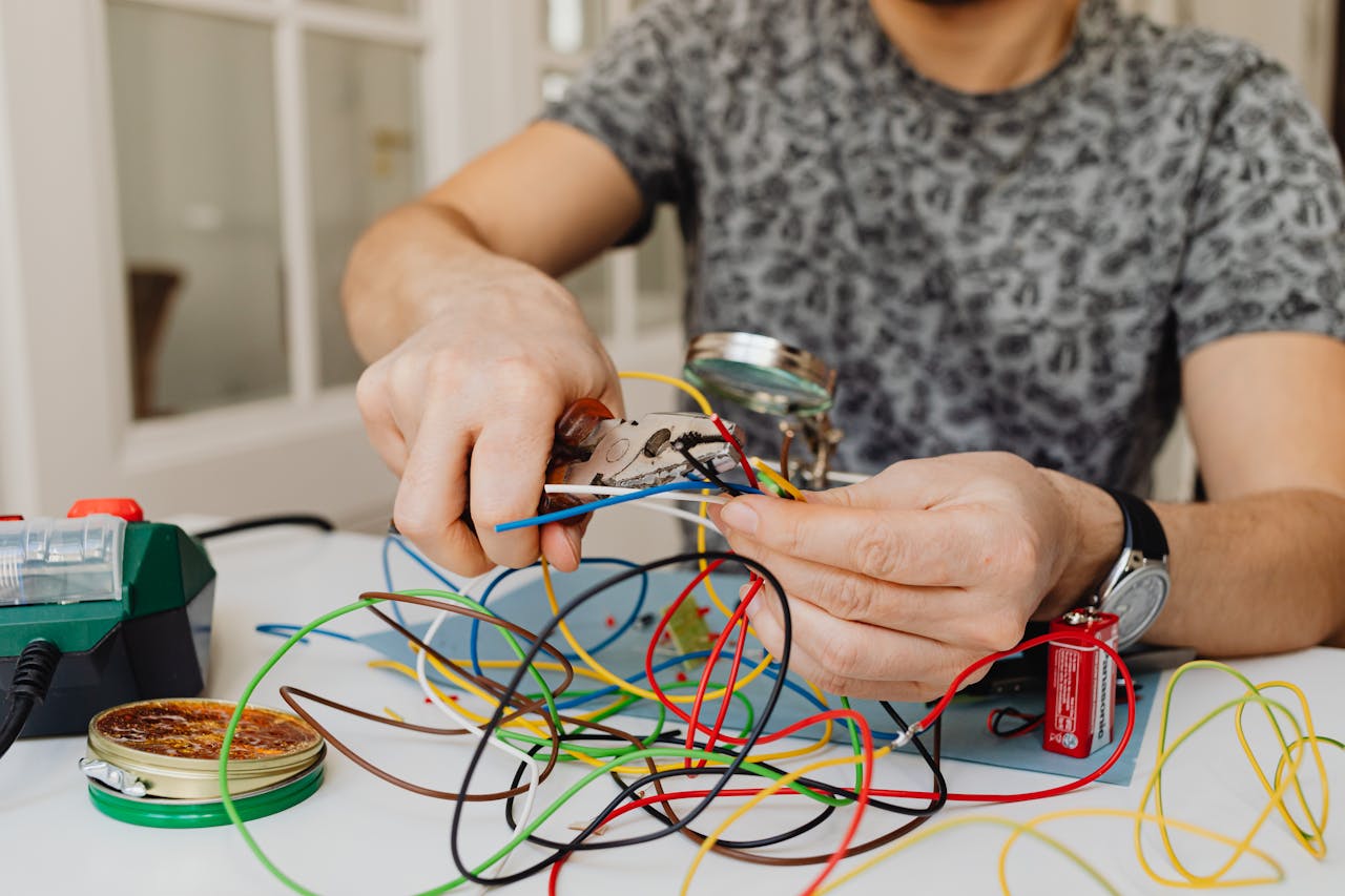 Person using pliers to cut through colorful electrical wires, showcasing DIY electronics work.